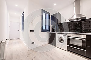 Newly installed kitchen with contemporary design with black wooden cabinets with matching appliances and light wooden floors