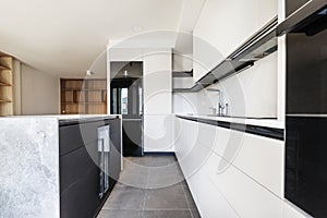 A newly installed modern kitchen with off-white handleless cabinets, steel faucets and an island with a wine fridge