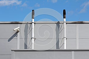 Newly installed narrow metal pipes used for ventilation with protective cap on top next to closed circuit TV CCTV security camera