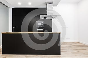 newly installed open plan kitchen with black cabinets, appliances and faucets and an island with a wooden countertop on laminated