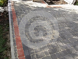 Newly laid gray and red pavement tiles edged with curbs in the yard