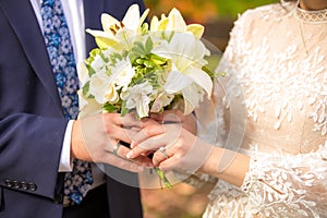 Newly married couple holding wedding bouquet of lilies