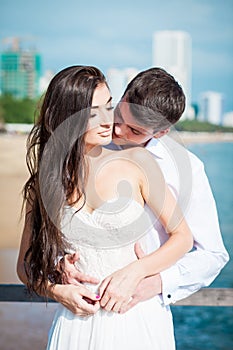 Newly married couple kiss each other after wedding in luxury resort. Romantic bride and groom relaxing near swimming