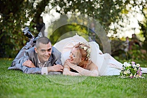 Newly-married couple lies on a grass