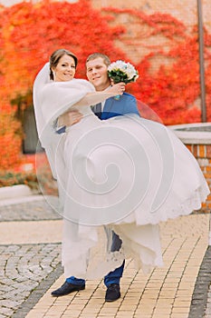 Newly married couple posing in park. Red creeping plant as background