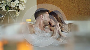 Newly married couple is relaxing in jacuzzi kissing, touching hands, talking and laughing. Romantic relationship
