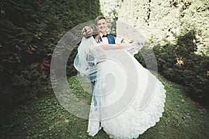 Newly married couple running and jumping in park while holding hands