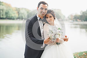 Newly married couple running and jumping in park while holding hands