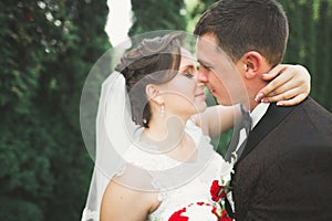 Newly married couple running and jumping in park while holding hands