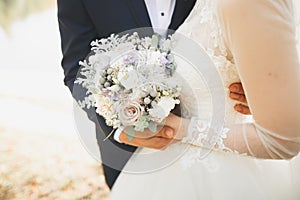 Newly married couple running and jumping in park while holding hands