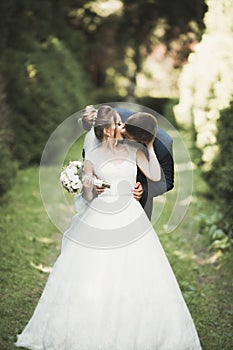 Newly married couple running and jumping in park while holding hands