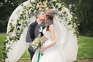 Newly married couple running and jumping in park while holding hands