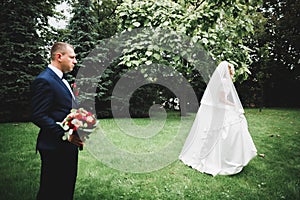 Newly married couple running and jumping in park while holding hands