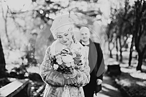 Newly married couple running and jumping in park while holding hands