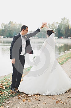 Newly married couple running and jumping in park while holding hands