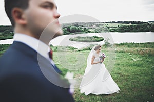 Newly married couple running and jumping in park while holding hands