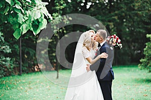 Newly married couple running and jumping in park while holding hands