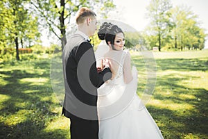 Newly married couple running and jumping in park while holding hands