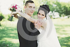 Newly married couple running and jumping in park while holding hands