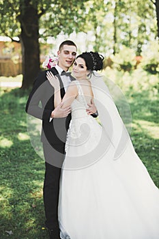 Newly married couple running and jumping in park while holding hands