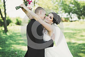 Newly married couple running and jumping in park while holding hands