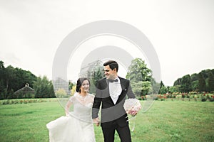 Newly married couple running and jumping in park while holding hands