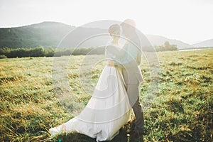 Newly married couple running and jumping in park while holding hands