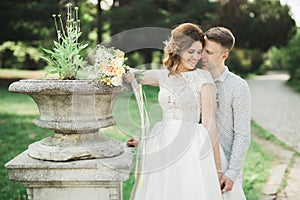 Newly married couple running and jumping in park while holding hands