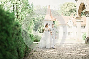 Newly married couple running and jumping in park while holding hands