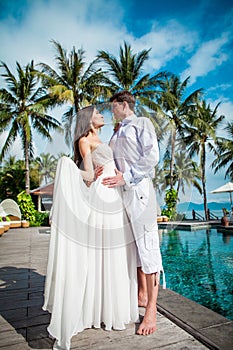 Newly married couple after wedding in luxury resort. Romantic bride and groom relaxing near swimming pool. Honeymoon.