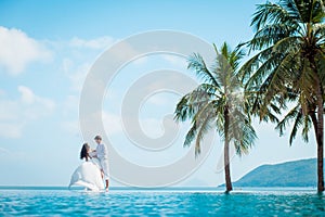 Newly married couple after wedding in luxury resort. Romantic bride and groom relaxing near swimming pool. Honeymoon.