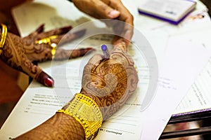 A newly married indian bengali wife with golden ornament and blacelet signing marriage registration form