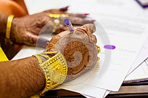 A newly married indian bengali wife with golden ornament and blacelet signing marriage registration form