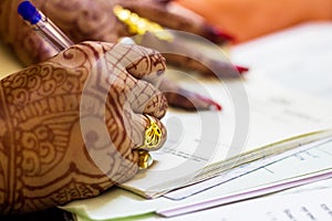 A newly married indian bengali wife with golden wedding ring signing marriage registration form