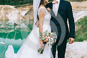 Newly married loving couple with rings on their hands and a bouquet of the bride hugging