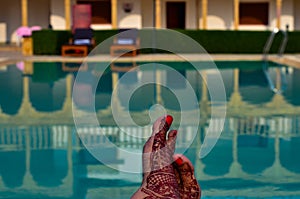 Newly married woman with henna feet in front of a swimming pool on her honeymoon in a resort in Jaisalmer, India