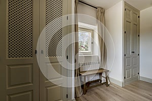 Newly renovated bedroom with built-in wardrobes with lattice doors and a square window in the middle