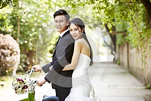 Asian wedding couple riding bicycle