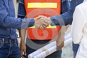 Newly wed couple is handshaking with engineering contractor at their under construction house to inspect building progress and