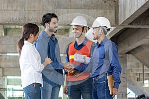 Newly wed couple is handshaking with engineering contractor at their under construction house to inspect building progress and