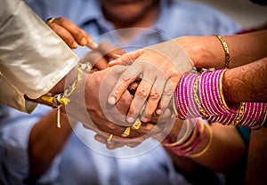 Closeup of Bride, Groom and their parents Joining Hands During an Indian Wedding Ritual