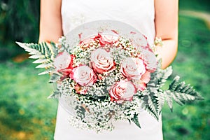 Newly Wed Woman Holding her Bridal Bouquet in a Green Garden