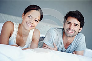 Newly-weds enjoying their new home. Portrait of a happy couple lying on their bed.