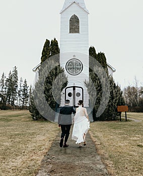 Newly weds running in front of old church holding hands
