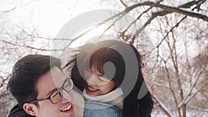 Newlywed asian couple having fun outside on Valentines day. Young man giving piggyback ride to his girlfriend