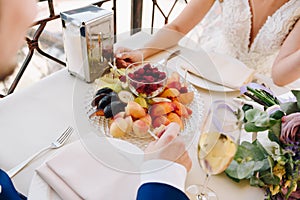 Newlywed bride and groom eating fruit and drinking champagne on their wedding day