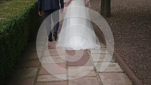 A newlywed caucasian couple a man and a girl walk forward on a path of tiles