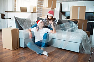 Newlywed couple celebrate Christmas or New Year in their new apartment. Young happy man and woman celebrating moving to