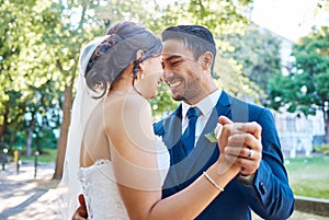 Newlywed couple dancing outside. Mixed race bride and groom enjoying romantic moments on their wedding day. Happy young