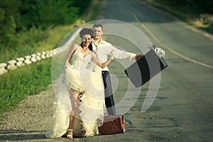 Newlywed couple hitchhiking on a road